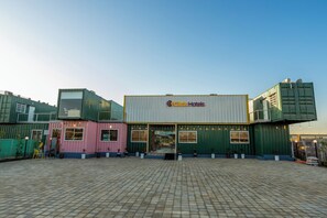 A hotel with a modern design, featuring a prominent sign and a spacious outdoor area with a tiled floor.