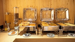 Een buffetopstelling met verschillende drank- en etensdispensers, een koffieapparaat en een sapdispenser.