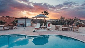 Ein Poolbereich mit Liegestühlen, einem Tisch und einem Sonnenschirm.
