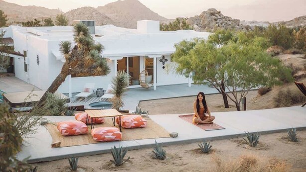 A modern white building with a patio area featuring outdoor seating and a yoga mat. - Villa Paloma • 4-Acre Stylish Retreat with Hot Tub (Yucca Valley)