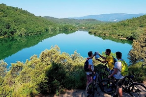 Un grupo de personas con bicicletas cerca de un lago rodeado de vegetación.