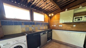 A compact kitchen with a washing machine, a dishwasher, a stove, and a microwave. - Chambre D'hôtes et Petit Déjeuner D'exceptionnel (Tourrettes)