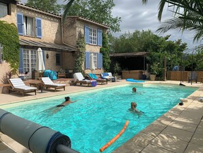Piscina con sillas de descanso y un área de estar techada.