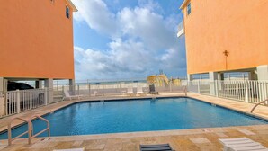 A swimming pool with a view of the beach, surrounded by a white fence, and a lifeguard tower in the background. - Top Floor Beachside Condo in Gulf Shores Sleeps 6 (Gulf Shores)
