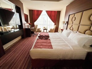 Una habitación de hotel con una cama grande, televisión, escritorio y una silla.