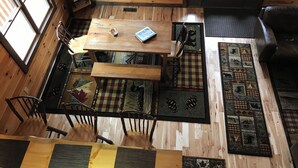A wooden cabin interior with a dining table, chairs, a bench, and a patterned rug. - Find peace, tranquility and nature—secluded cabin on 42 acres with fishing pond (Warsaw)