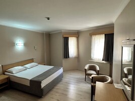 A hotel room with a bed, two chairs, a small table, and a mirror.