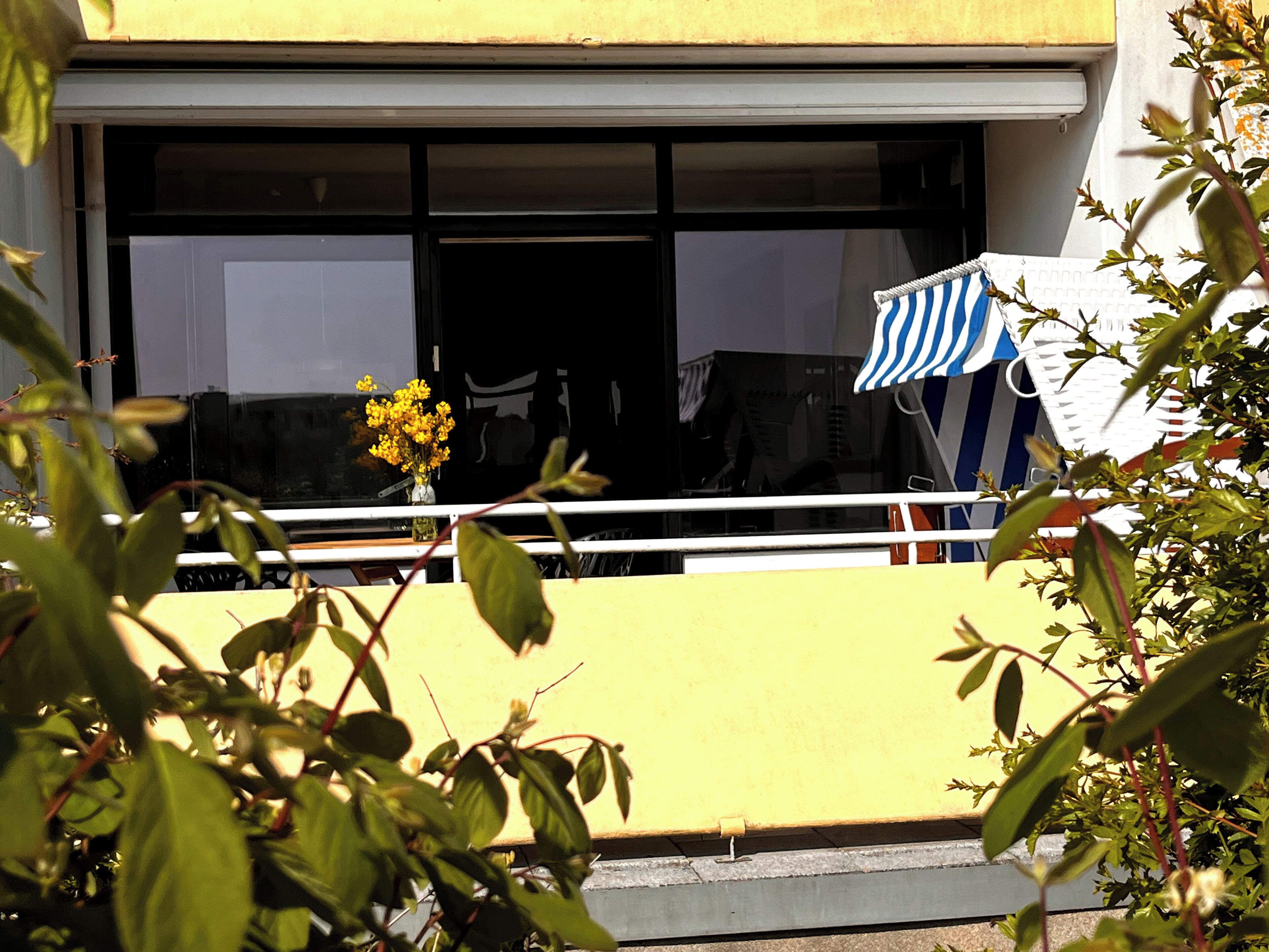 A yellow building with a large window and a blue-striped awning.