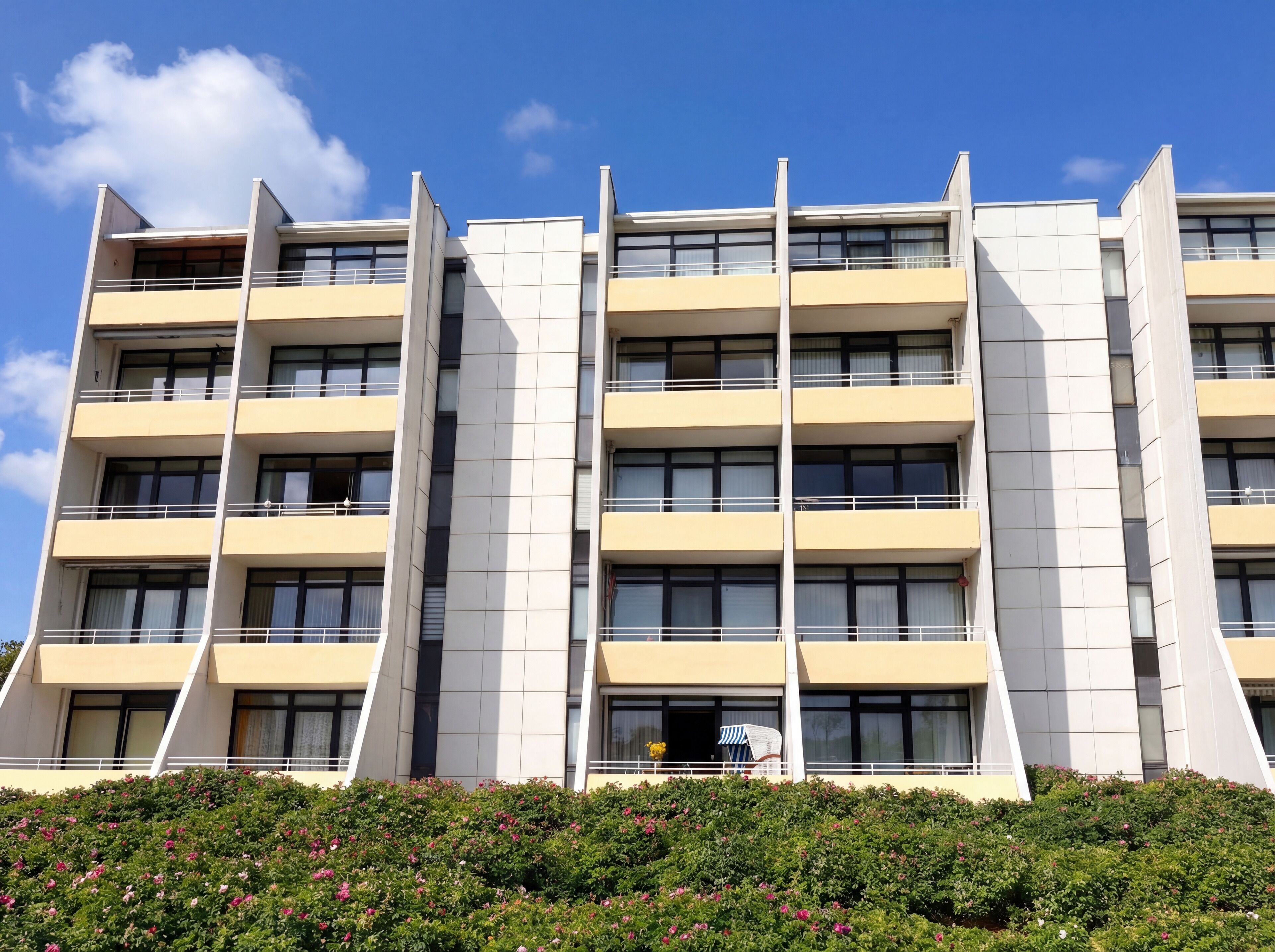 Un edificio de varios pisos con un diseño arquitectónico moderno, que cuenta con balcones y grandes ventanales.