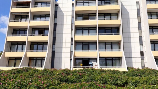 Un edificio de varios pisos con un diseño arquitectónico moderno, que cuenta con balcones y grandes ventanales.