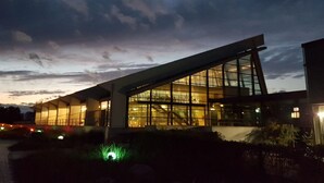 Un bâtiment moderne doté de grandes fenêtres en verre et d’un toit en pente.