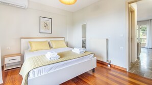 A bedroom with a bed, bedside table, and a hanging light fixture. - Seaview Portside apartment (Corfu)