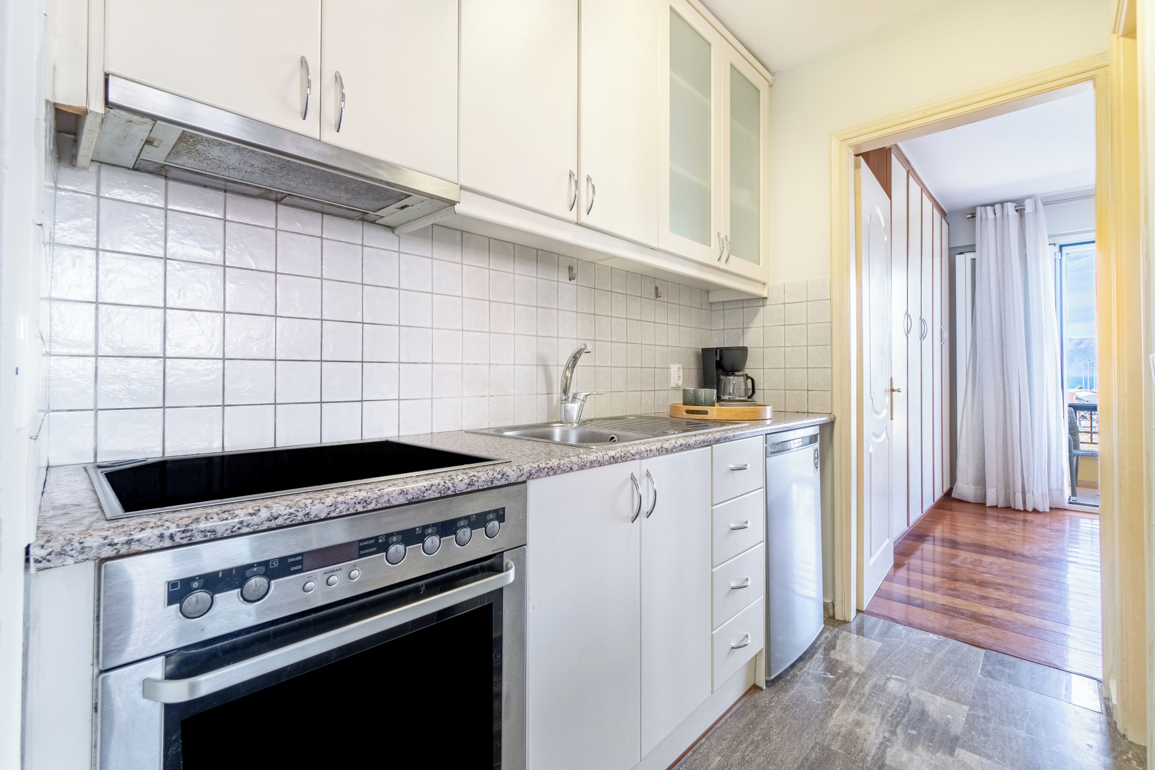 A kitchen with white cabinets, a stainless steel stove, and a tiled backsplash.