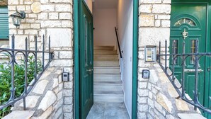 A stone building with a green door and a staircase leading inside. - Seaview Portside apartment (Corfu)