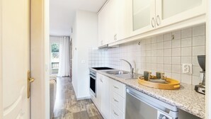 A modern kitchen with white cabinets, a granite countertop, and a built-in oven. - Seaview Portside apartment (Corfu)