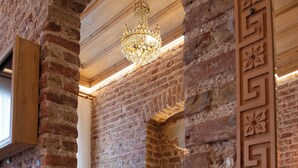 A room with exposed brick walls, a chandelier, a green sofa, and a patterned rug. - Eagle's Nest Boutique Hotel (Istanbul)