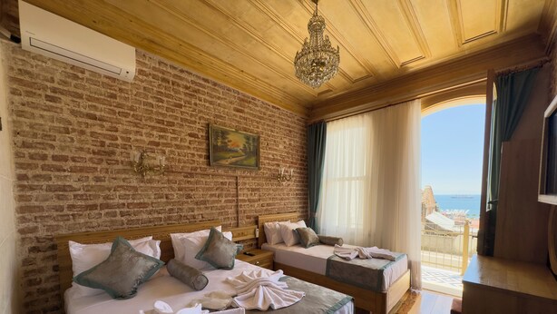A hotel room with two beds, a brick wall, a chandelier, and a view of the sea. - Eagle's Nest Boutique Hotel (Istanbul)
