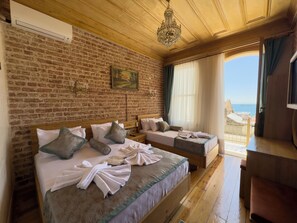 Een hotelkamer met twee bedden, een bakstenen muur, een kroonluchter en uitzicht op zee.