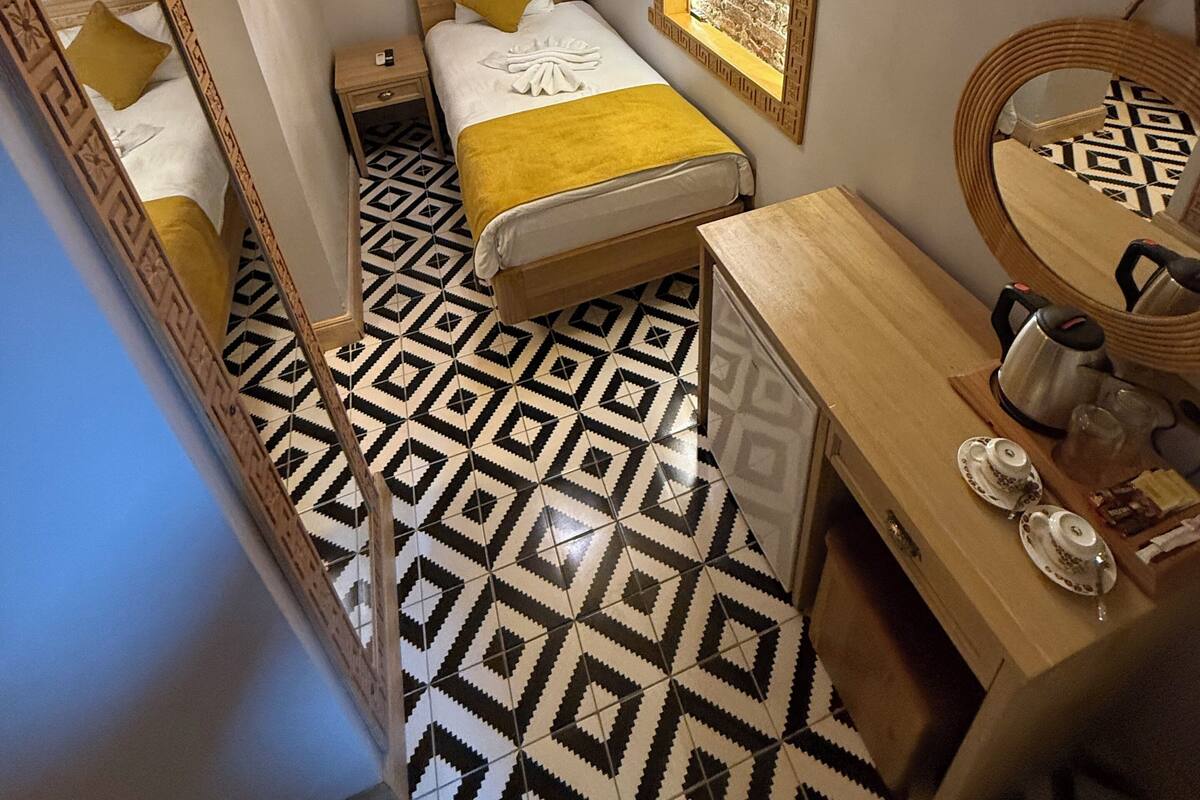 Ein kleines Hotelzimmer mit Bett, Nachttisch und Schreibtisch.