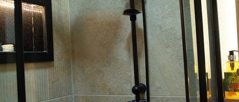 A shower with a handheld head and a handheld showerhead, mounted on a tiled wall.