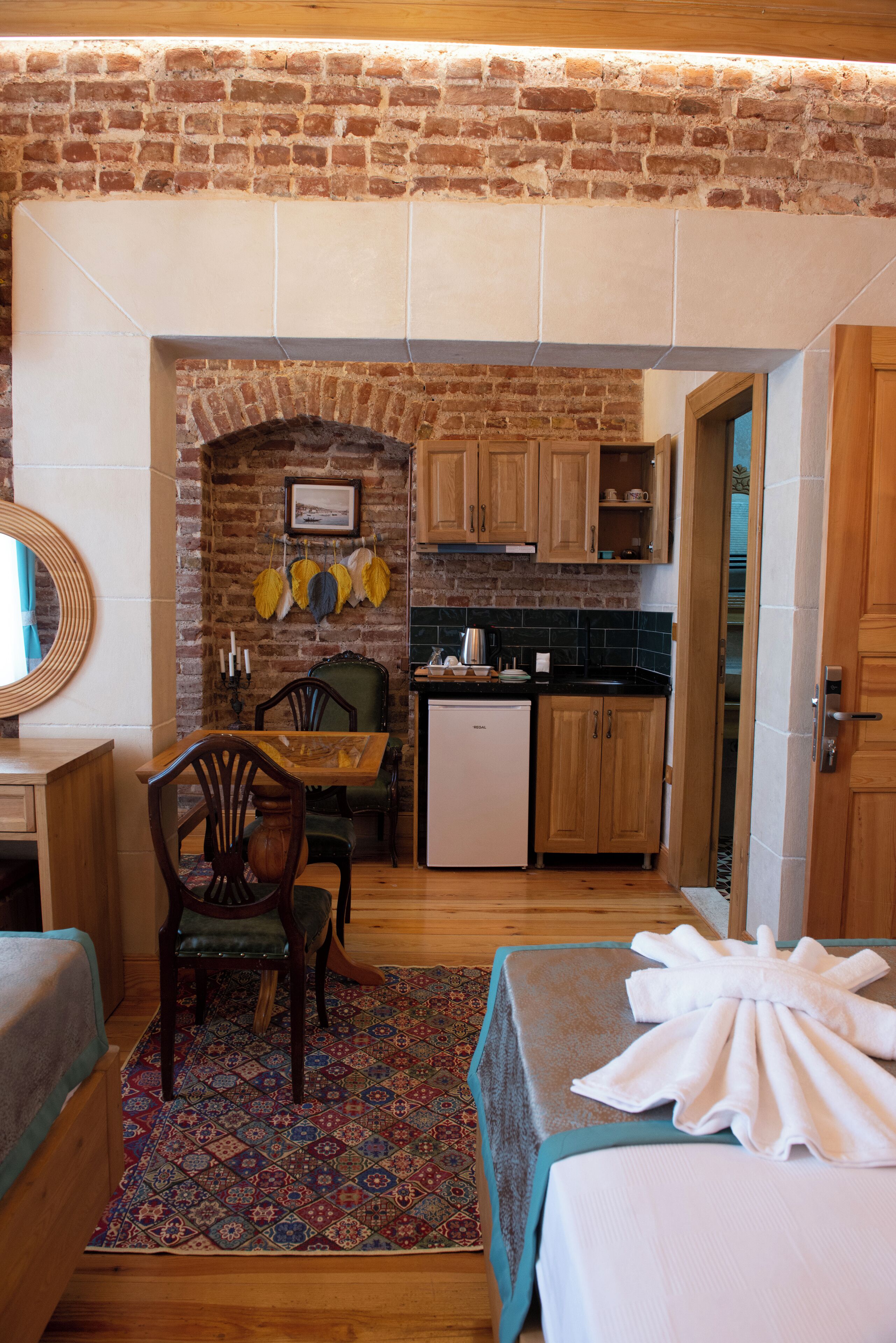 A compact kitchen with a brick wall, wooden cabinets, and a small refrigerator.