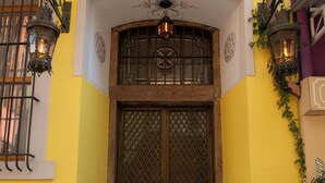 A wooden door with a decorative metal grille, flanked by two wall-mounted lanterns, leading to a set of marble steps. - Eagle's Nest Boutique Hotel (Istanbul)
