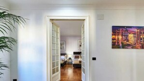 A hallway with wooden flooring, white walls, and a painting of ancient ruins. - A Blend of Historical Elegance and Modern Comfort (Roma)