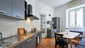 A modern kitchen with grey cabinets, a wooden countertop, and a dining area with a table and chairs. - A Blend of Historical Elegance and Modern Comfort (Roma)