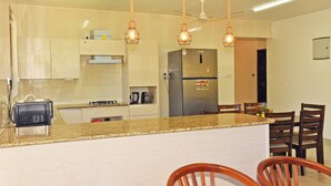 A modern kitchen with granite countertops, stainless steel appliances, and wooden chairs. - Cozy studio in peaceful Diani located in a leafy and serene neighborhood (Diani)
