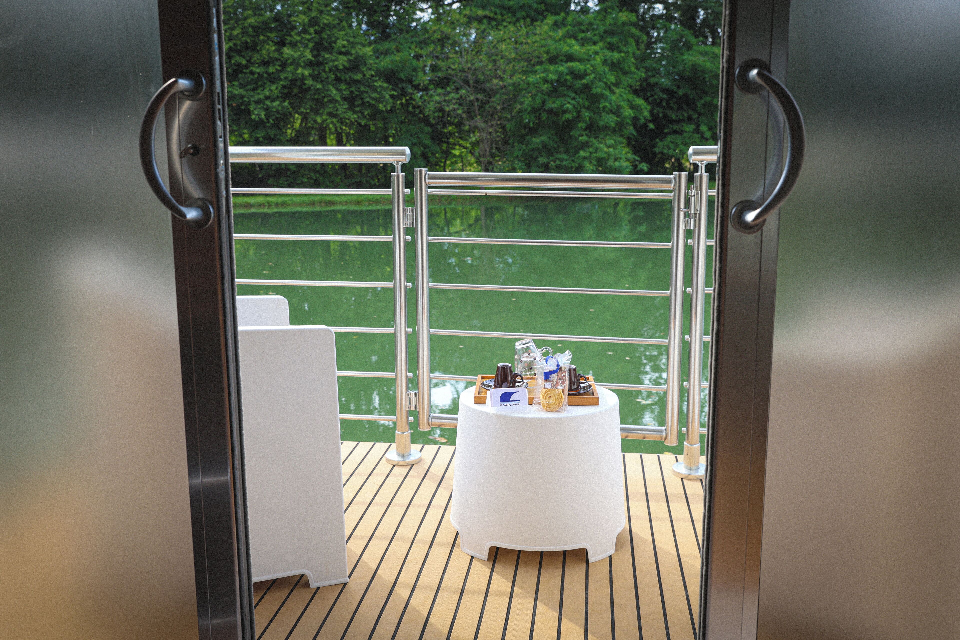 Ein Balkon mit Esstisch, Metallgeländern und Blick auf Grünflächen.
