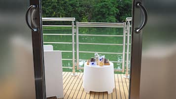 Ein Balkon mit Esstisch, Metallgeländern und Blick auf Grünflächen.