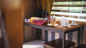 A kitchen area with a wooden table, a coffee maker, and a window with blinds. - FLOATING DREAM (Fiano)