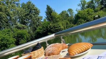 A table with food items and a view of a lake surrounded by trees.