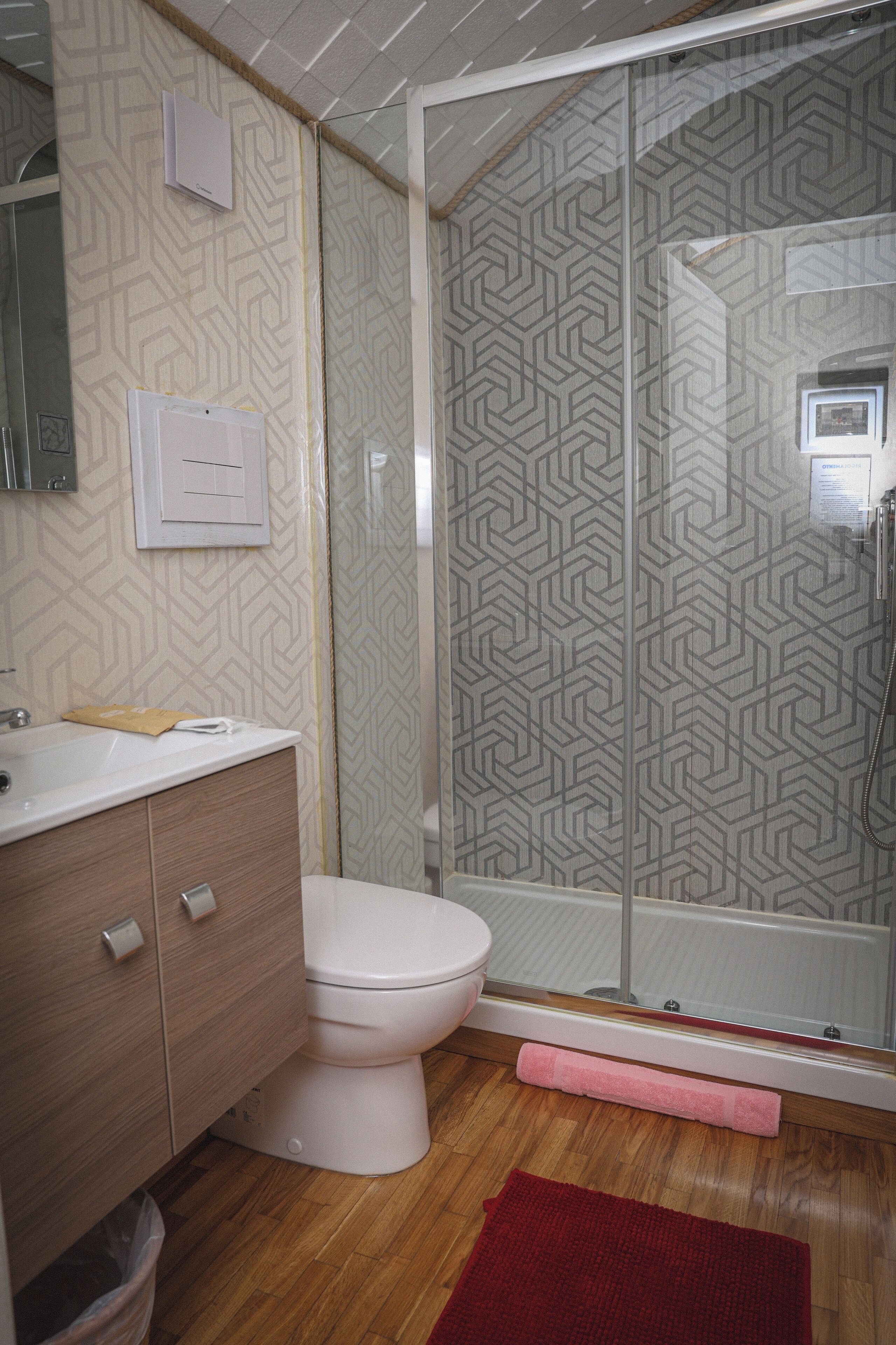 Une salle de bain comprenant des toilettes, un lavabo, un miroir et un espace douche.