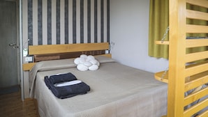 A small, single-bed room with a striped wall, a wooden headboard, and a green curtain. - FLOATING DREAM (Fiano)