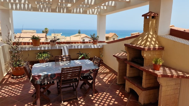 An outdoor patio with a table and chairs, a brick oven, and potted plants. - Tlidjene ain taya (Algiers)