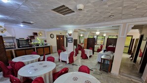 A banquet hall with round tables covered with white tablecloths and red chairs. - Tlidjene ain taya (Algiers)
