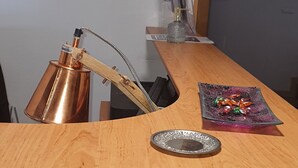 A wooden reception desk with a copper lamp, a decorative plate, and a glass container with ornaments. - Radio Hotel Bratislava (Bratislava)
