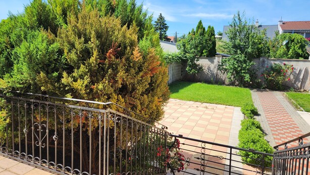 A courtyard with a paved walkway, a metal fence, and various trees. - Radio Hotel Bratislava (Bratislava)