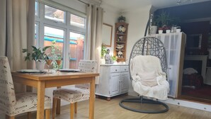 Een eetruimte met een houten tafel en stoelen, een hangstoel en een kast met decoratieve objecten.