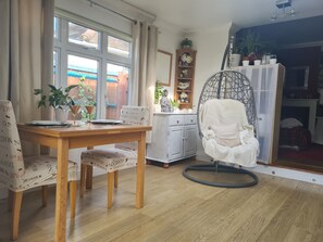 Enjoy a meal for two at the dining table, with a comfortable chair by the window offering a view of the outdoors.