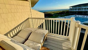 Ein Balkon mit Holzdeck, weißer Reling und beigen Kissen.