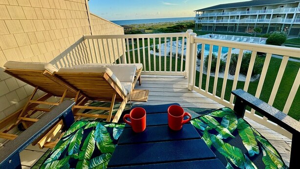 Ein Balkon mit Blick auf das Meer und ein Gebäude im Hintergrund.