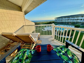 A balcony with a view of the ocean and a building in the background. - SSV 205 - Sunshine Oasis: Oceanfront condo in Oak Island, sleeps 8 with pool access! (Oak Island)
