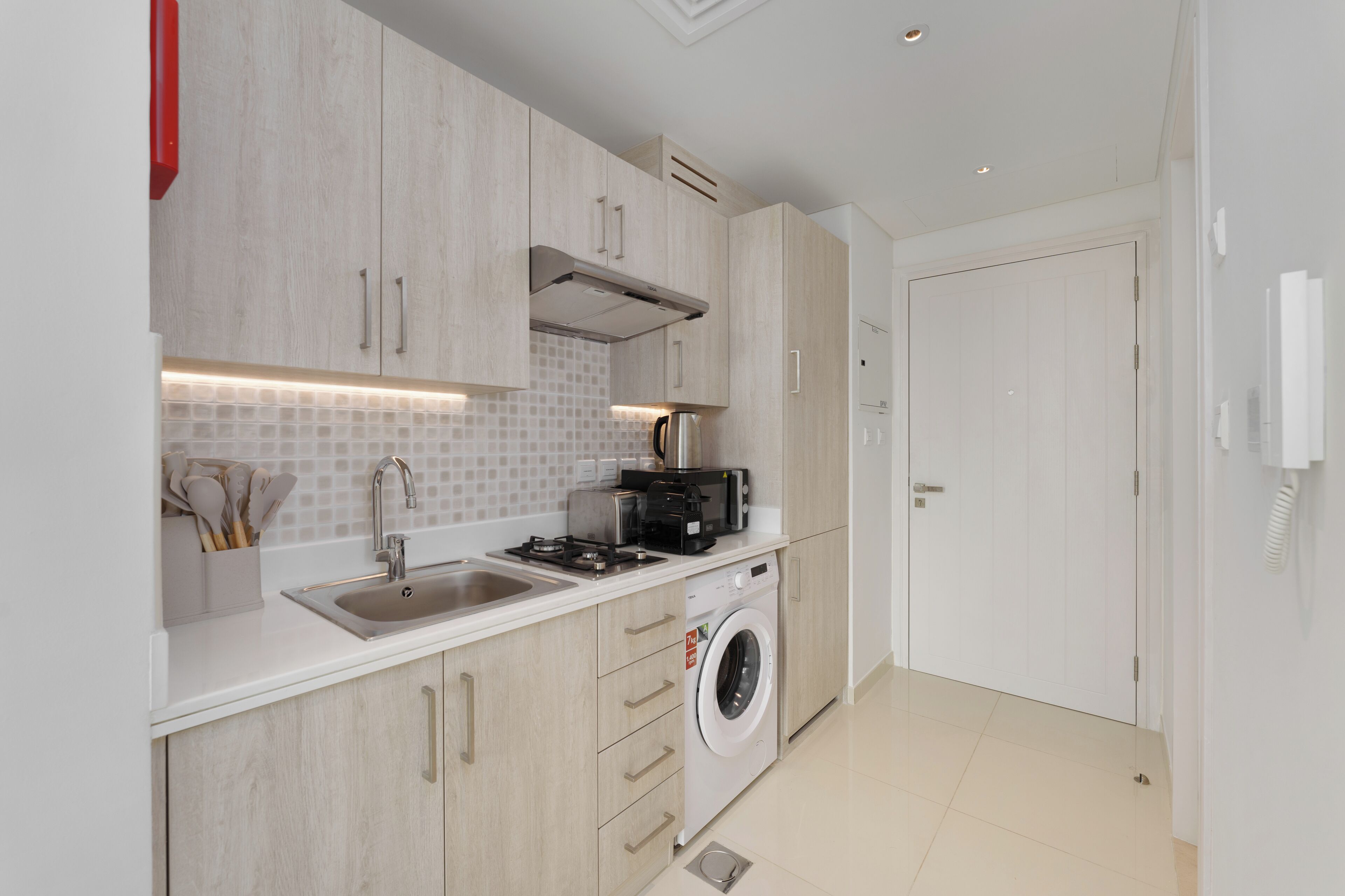 A modern kitchen with a built-in washing machine, a sink, and a toaster.