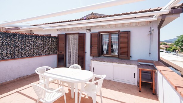 A patio with a white table and chairs, a small wooden bench, and a white cabinet. - Corallo Blu in San Teodoro (San Teodoro)