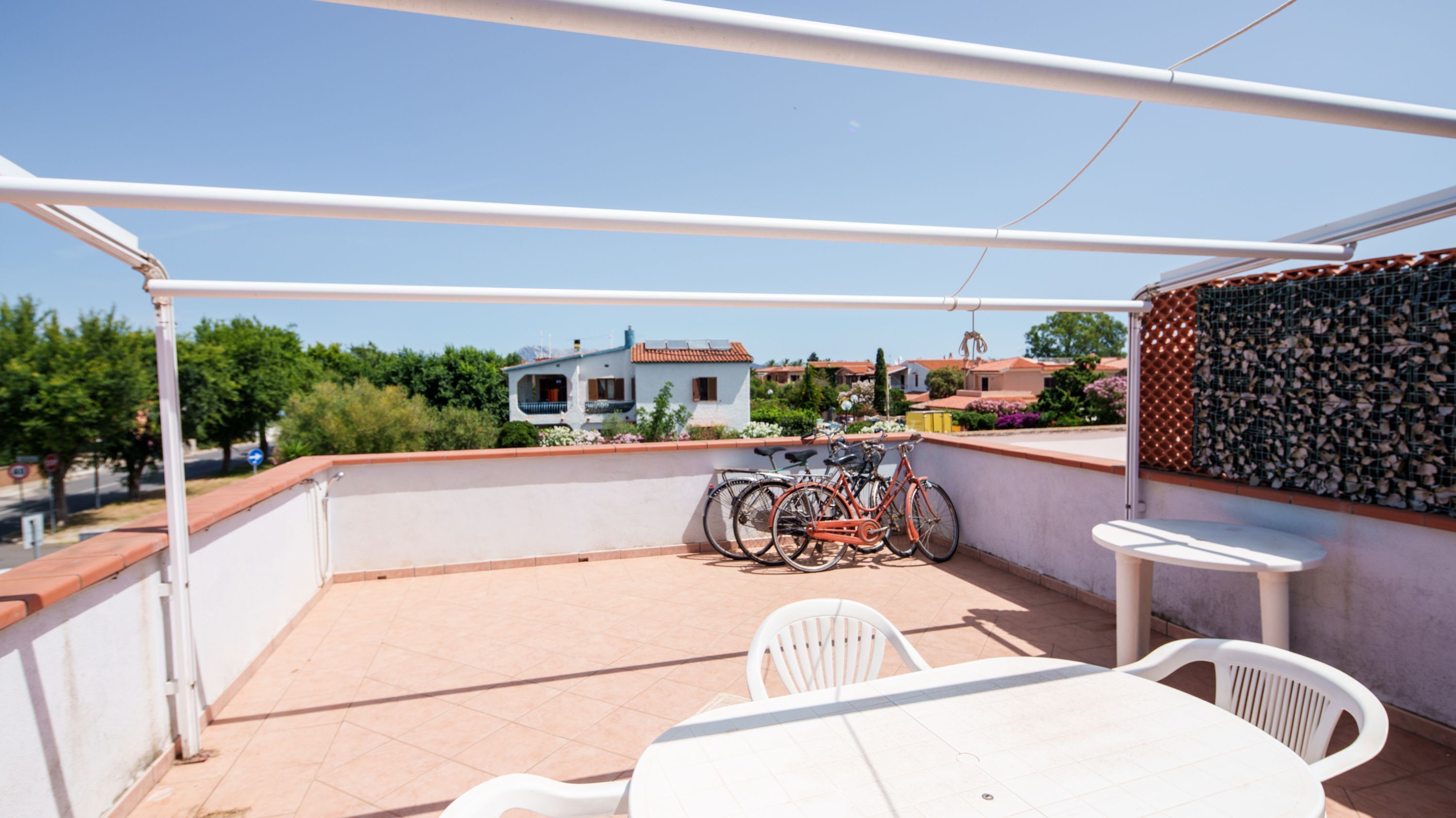A terrace with a table and chairs, a bicycle, and a view of houses in the background.