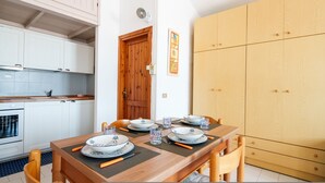 A dining area with a wooden table set for four, surrounded by white cabinets and a wooden wardrobe. - Corallo Blu in San Teodoro (San Teodoro)