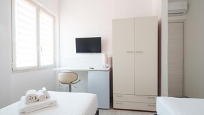 A hotel room with a bed, a desk with a computer, a wardrobe, and a TV on the wall. - Das Halte Haus - Room 303 (Olbia)