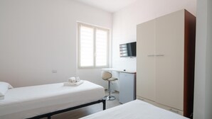 A small, clean room with a bed, a desk, a chair, and a wardrobe. - Das Halte Haus - Room 303 (Olbia)